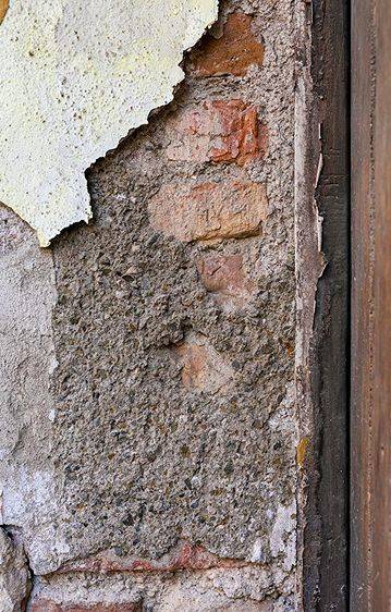 Ziegelwand hinter gebrochener Fassade und Dämmung