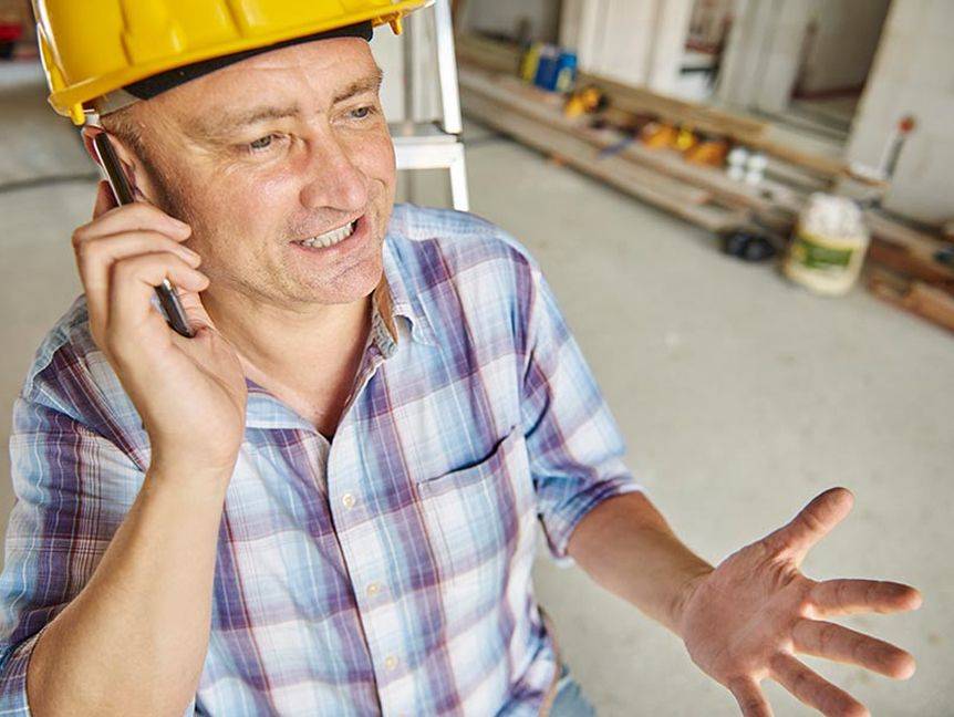 Aufgeregter Handwerker telefoniert auf dem Handy, gestikuliert